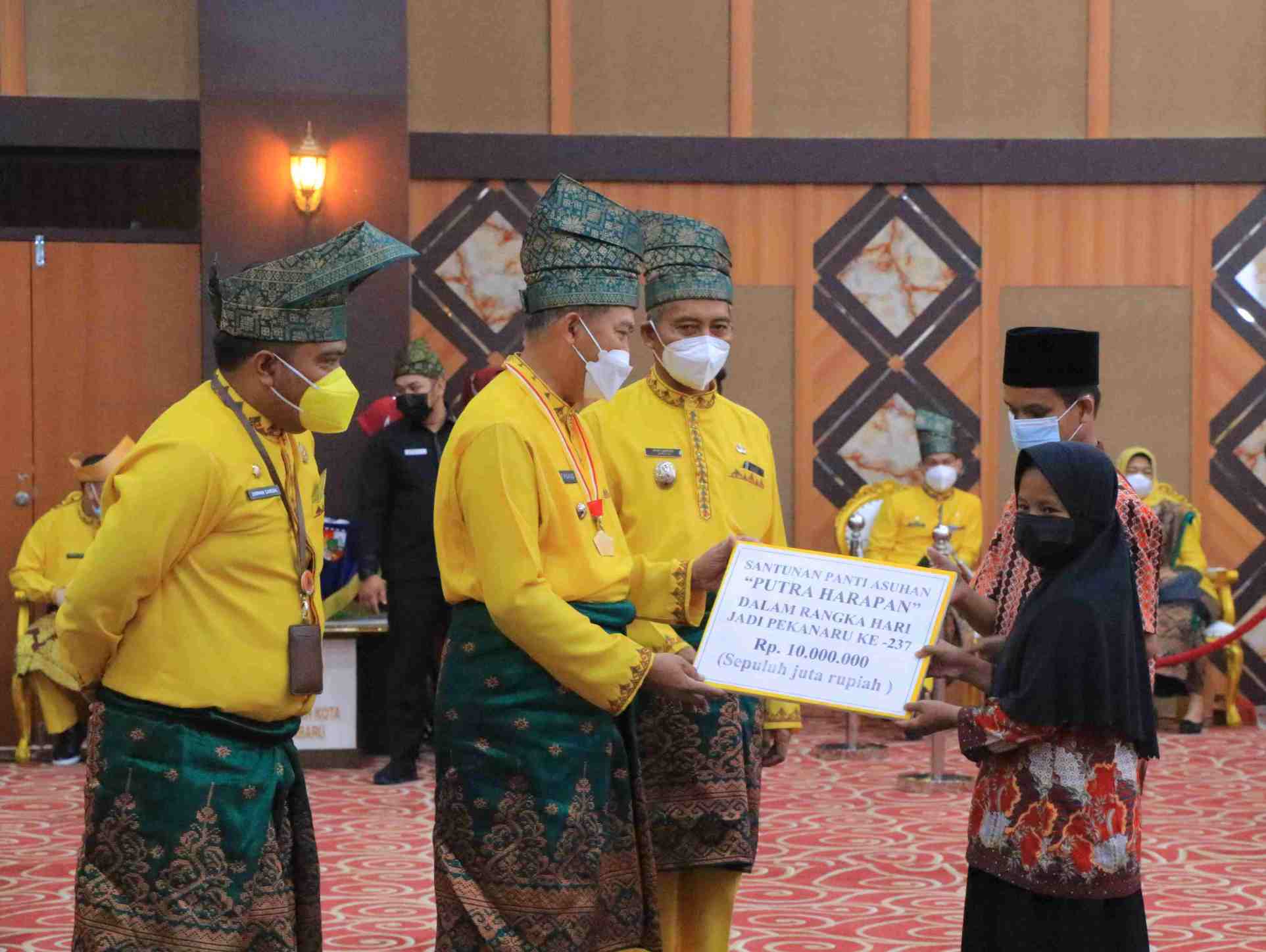 Wali Kota Pekanbaru Firdaus didampingi Wakil Wali Kota Ayat Cahyadi saat menyerahkan bantuan secara simbolis untuk memotong tumpeng dalam perayaan hari jadi Kota Pekanbaru.